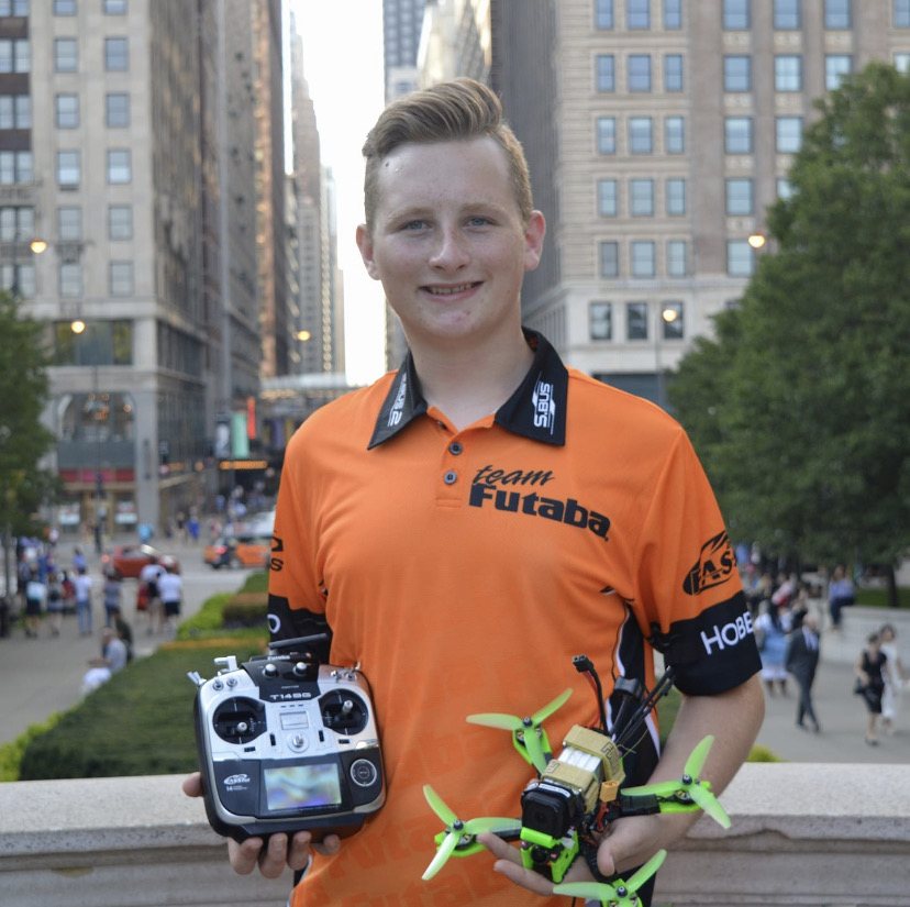 Nicholas Trevino in an orange FPV team shirt holding drone equipment